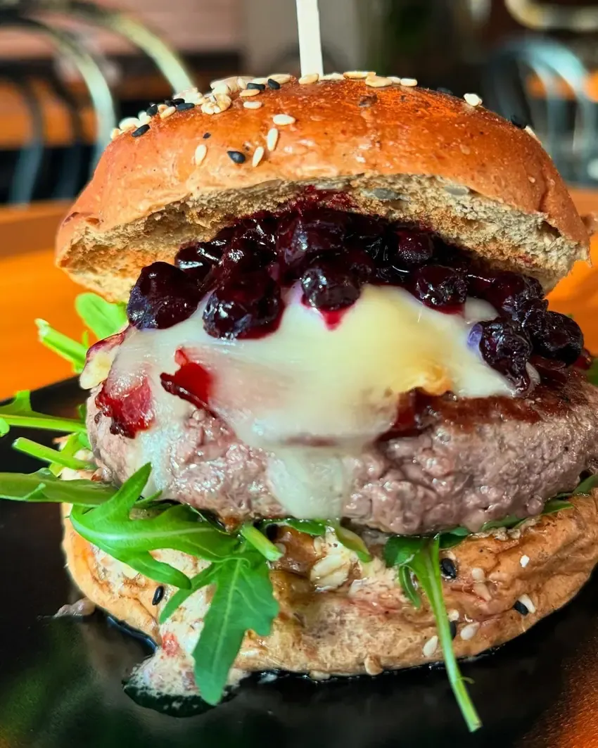 Hamburguesa con queso cremoso, confitura de frutos rojos y rúcula en pan de cereales